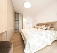 A bright bedroom with wood-patterned flooring and built-in wardrobes in a 3-room apartment.