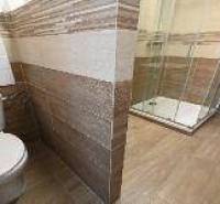 Bathroom in a 2-room apartment with a toilet and tiles with a wooden decor.
