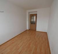 A room in a 2-room apartment with a wooden decor floor and white walls.