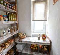 Pantry with shelves, fruits, vegetables, and groceries in a 2-room apartment, light coming through the window.