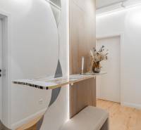 A hallway in a 3-room apartment with a minimalist table, mirror, and floor with a wooden decor.