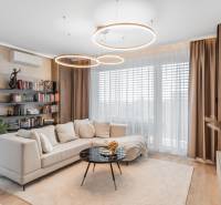 Living room with wood-patterned flooring in a 3-room apartment, comfortable sofa, bookshelf.