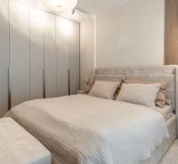 A bright bedroom with a built-in wardrobe and a bed in a 3-room apartment.