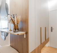 Entrance hallway with a mirror, wardrobe, and decoration in a 3-room apartment with a wooden decor floor.