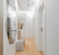A bright hallway with a mirror, a bench, and a wooden decor floor in a 3-room apartment.