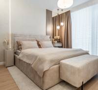 Bright bedroom with a comfortable bed, beige curtains, and a wood-patterned floor.