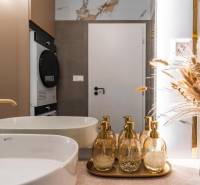 Bathroom with a sink, gold dispensers, and decorative natural decorations in a 3-room apartment.