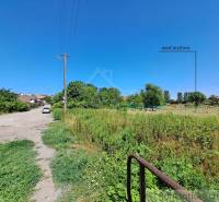 The path leads to the plots - housing in Hosťová with a view of greenery and houses.