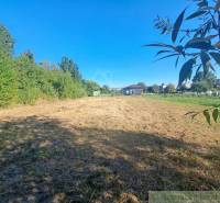 A residential plot surrounded by greenery in Hosťová under sunny weather.