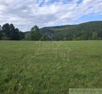 Extensive meadow plots for housing in Horný Tisovník, surrounded by forests and hills.