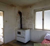 A room in a family house with a tiled stove and worn-out walls.