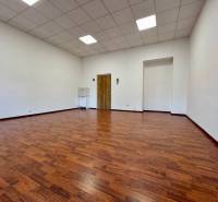 An office with a wooden decor floor, white walls, and a suspended ceiling.