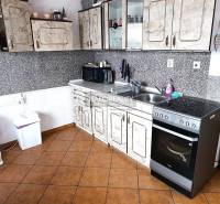 A kitchen with tiles and a kitchen unit in a 2-room apartment.