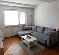Living room of a two-room apartment with a corner sofa and a coffee table on a floor with a wooden decor.
