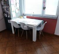 Kitchen of a 2-room apartment with a dining table, white chairs, and a window.