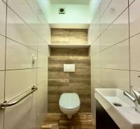 Bathroom in a 2-room apartment with a wooden decor floor and white tiles.