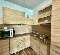 A kitchen with built-in cabinets and a wooden decor floor in a 2-room apartment.