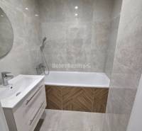 A bathroom with a shower faucet and a bathtub in a 3-room apartment.