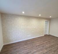 A room with white walls, a wooden decor floor, and built-in lights in a 3-room apartment.