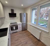 A kitchen in a 3-room apartment with white cabinets and a wood-patterned floor.