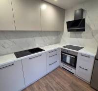 A kitchen with white cabinets and a wood-patterned floor in a 3-room apartment.