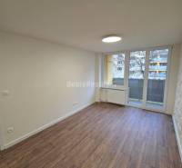 A room with a wooden decor floor and large windows in a 3-room apartment.