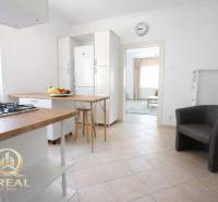 A kitchen with a bar counter in a studio apartment and fruit on the table.