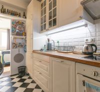 A kitchen in a 2-room apartment with white cabinets, black and white checkered tiles.
