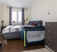 Bedroom in a 2-room apartment with a bed, dresser, and baby crib.
