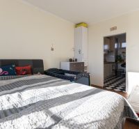 Bedroom in a 2-room apartment with a bed and a passage to the kitchen. Floor with wood decor.