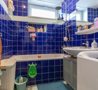 A bathroom with blue tiles, a sink, a bathtub, and a washing machine in a 2-room apartment.