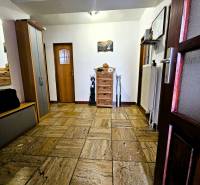 Hallway with ceramic tiles, wooden doors, and a wardrobe in a family house.