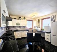 A kitchen in a family house with black glossy tiles and white furniture.