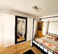 A bedroom in a family house with a bed, a carpet, and a wardrobe with a mirror.