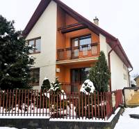 A family house in Kameňany with a snowy yard and a red fence.
