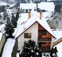 A family house in Kameňany covered with snow, overlooking snow-covered fields and hills.