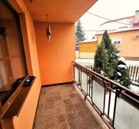 A balcony of a family house in Kameňany with a view of a snowy garden and a tree.