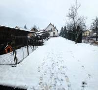 A family house in Kameňany with a snowy yard, surrounded by a garden and trees.