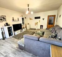Living room in a family house with a wooden decor floor, gray sofa, and modern lighting.