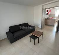 Living room in a two-room apartment with a black sofa and a small table.