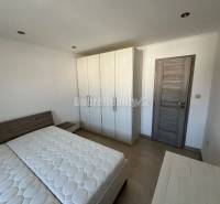 Bedroom in a 2-room apartment with a bed and a wardrobe, floor with wooden decor.