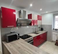 A kitchen in a 2-room apartment with built-in appliances and a floor with a wooden decor.