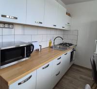 A kitchen with light furniture, a sink, and appliances in a 2-room apartment on Študentská Street.