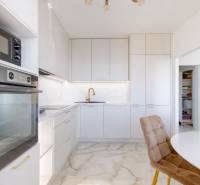A kitchen in a 3-room apartment with white cabinets and a stone floor.