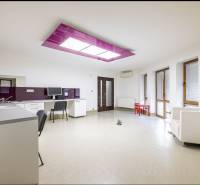 A kitchen with white furniture, a purple ceiling panel, and light walls in a family house.