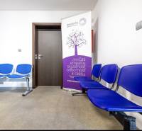 A waiting room in a family house with blue chairs and an advertising banner.