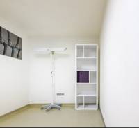A room with a shelving unit, a lamp stand, and a minimalist painting in a family house.
