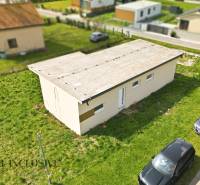 A cottage in Vojka nad Dunajom with a flat roof and cars parked on the grassy area.