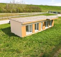 Cottage in Vojka nad Dunajom on a grassy plot with a road in the background.