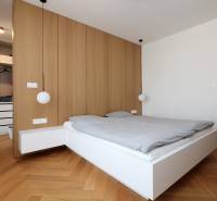 Bedroom in a 4-room apartment with a bed, wooden decor flooring, and a wardrobe.
